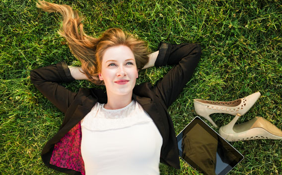 Young independent woman relaxing on grass in park