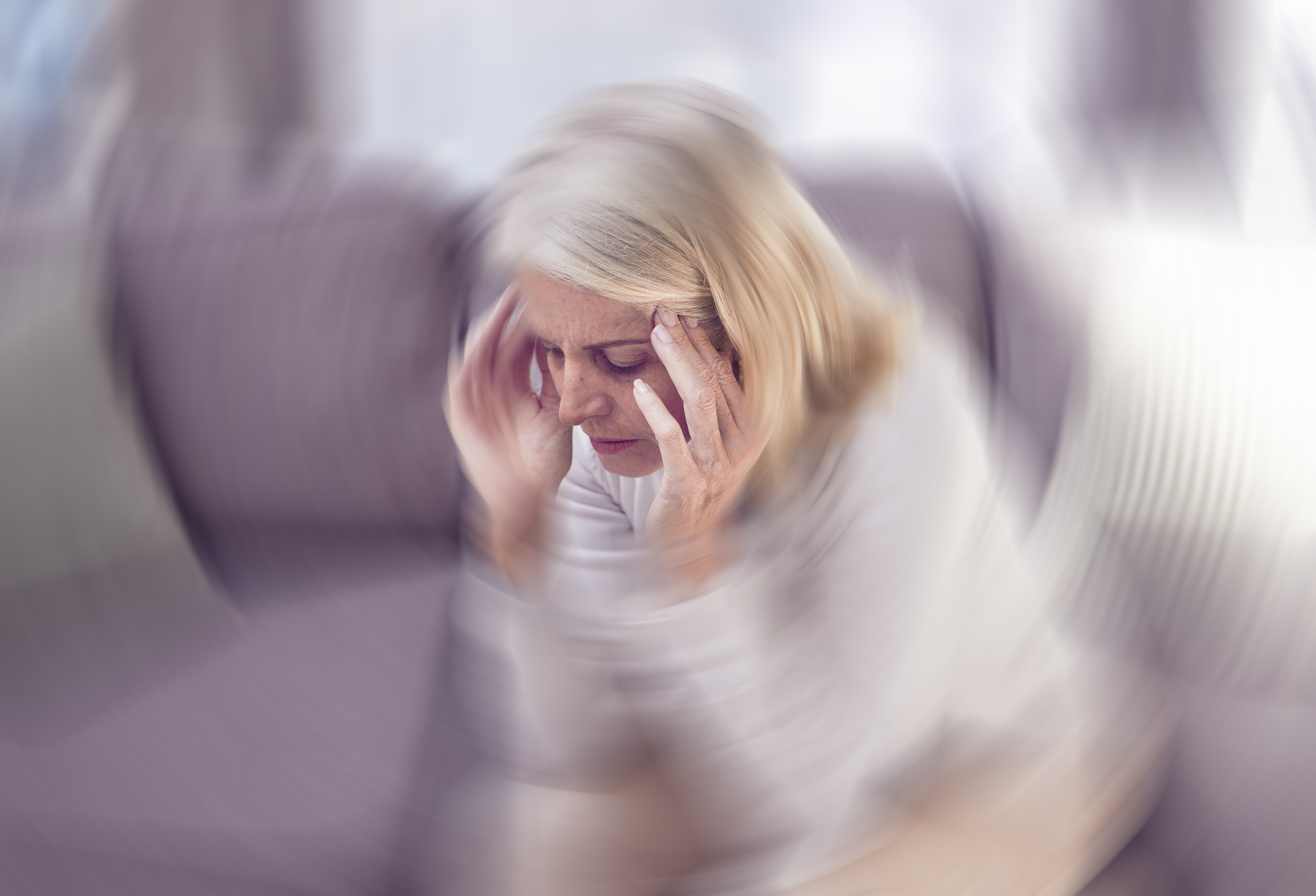 Woman holding head and wall with blurry background