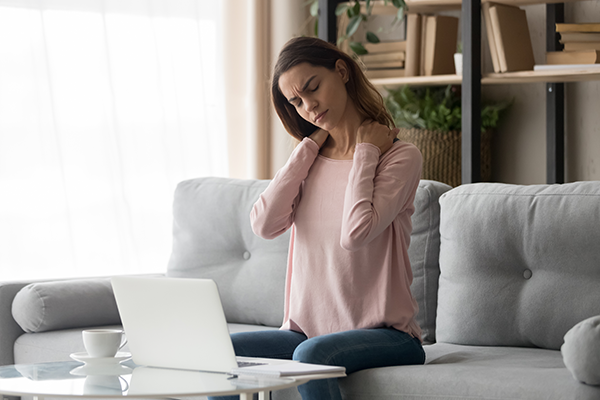 Woman sitting and holding her neck in pain 