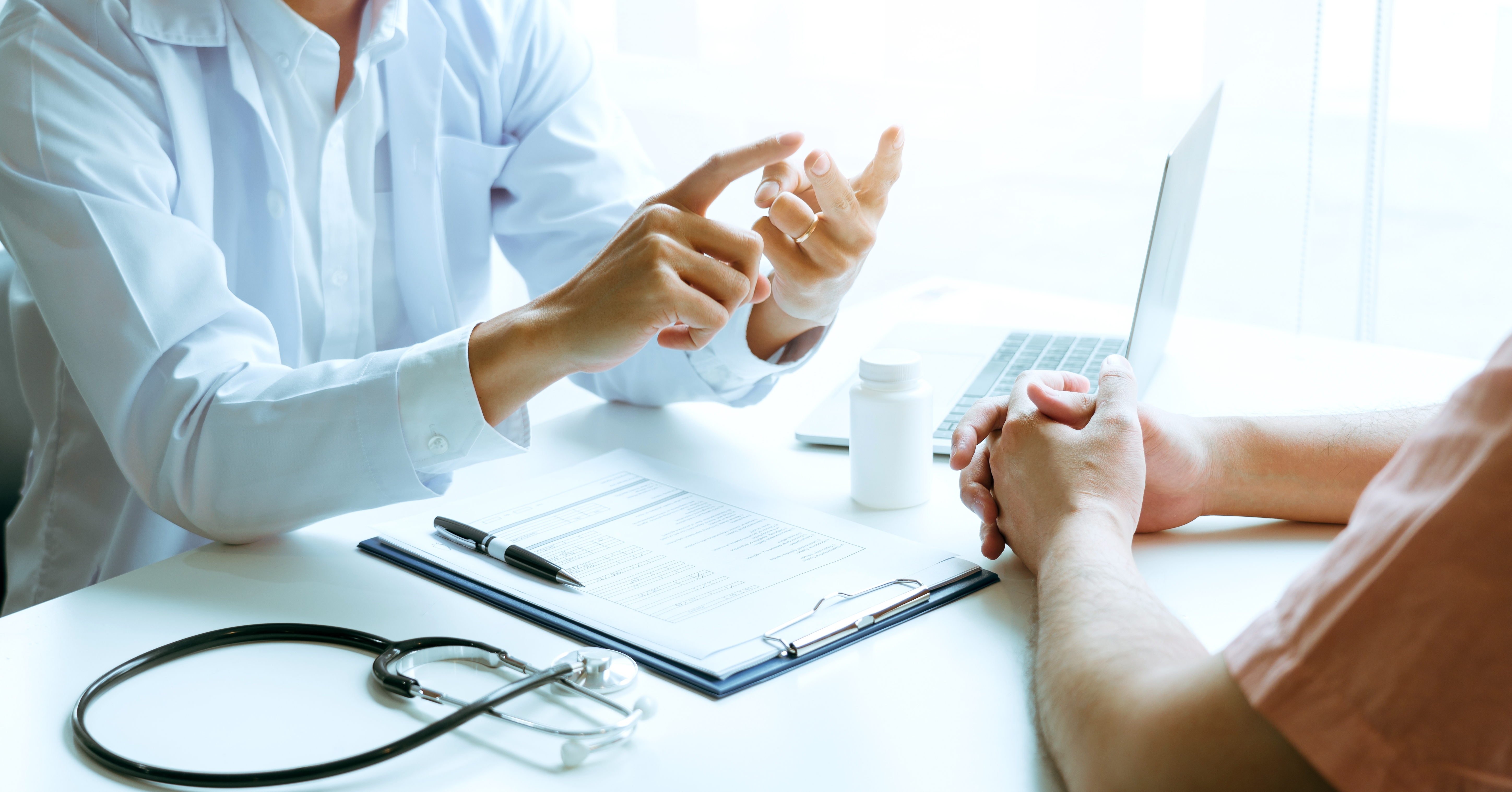 Healthcare professional counting explaining with hand gestures with laptop, medicine, clipboard and stethoscope on the desk