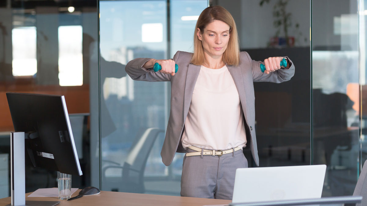 Beautiful and happy woman doing sports exercises in the office at work, during a break, business woman monitors health engaged in fitness 