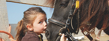 Child giving horse a kiss
