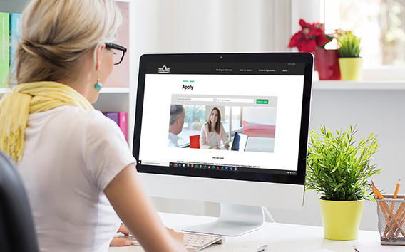 Woman sitting in front of a computer and searching for a job to apply to
