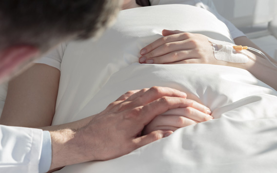 Man holding hand of person in sick bed