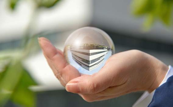 Hand holding a crystal ball which reflects a Grünenthal building from our Campus in Aachen, Germany