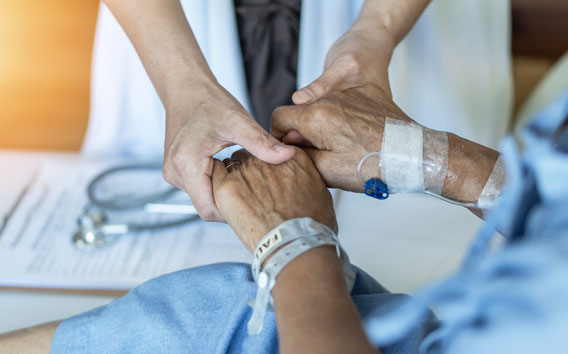 Elderly senior aged patient on bed with geriatric doctor holding hands for trust and nursing health care, medical treatment, caregiver and in-patient ward healthcare in hospital