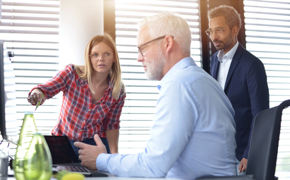 Three Grünenthal employees in conversation with each other in front of a pc